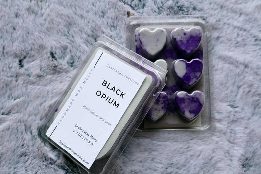 Heart-shaped Black Opium wax melts in a container on a textured surface